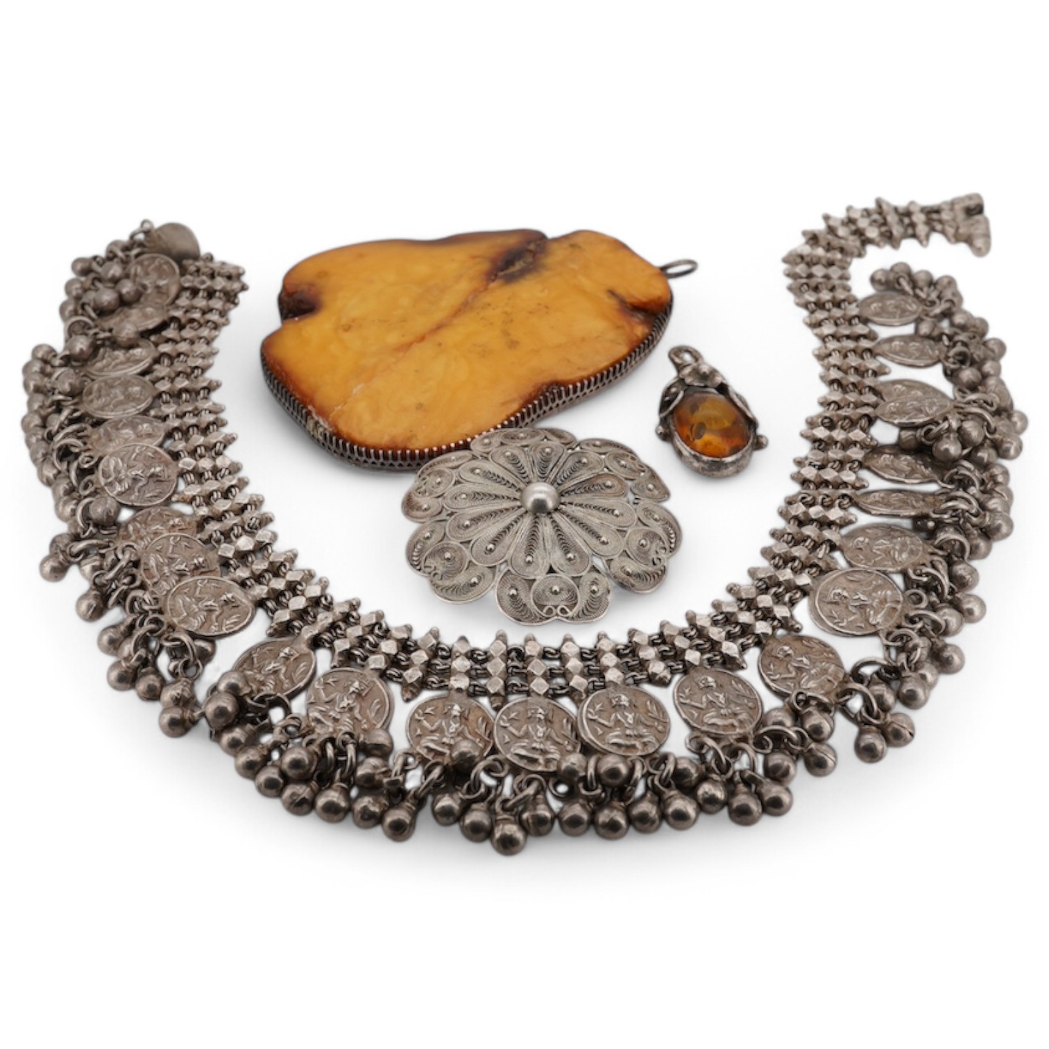 An Indian white metal fringe necklace, 37.5cm, a large antique white metal mounted amber pendant(a.f.), one other later smaller amber pendant and a filigree brooch. Condition - poor to fair